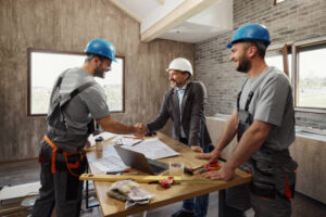 Three ADU contractors in Los Angeles discuss construction materials around a table at a residential job site