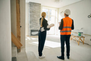 Two expert remodeling contractors in Hollywood discussing plans in an unfinished home, surrounded by construction materials for a home renovation