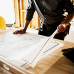 A remodeling contractor near Encino stands in front of a blueprint, wearing a hard hat, indicating a construction or architectural project.