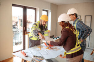 Three remodeling contractors near Encino in hard hats collaborating on a building project at a construction site