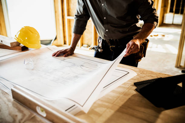 A remodeling contractor near Encino stands in front of a blueprint, wearing a hard hat, indicating a construction or architectural project.