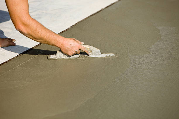 A man operates a cement mixer, highlighting the hands-on process involved in the cement vs concrete preparation for a construction project.