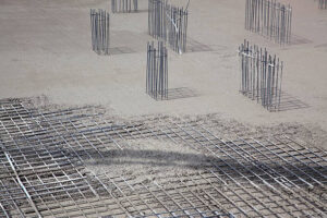 A construction site displaying metal rods and concrete, emphasizing the development of a concrete foundation.