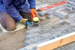 A man laying bricks on a patio, focused on the construction of a new brick surface for outdoor use.