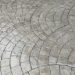 A concrete patio with a distinct circular design, emphasizing contemporary patio design, outdoor construction, and modern aesthetics for a stylish and functional space.