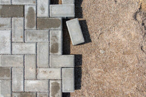 A brick walkway featuring a single brick resting on the ground, showcasing patio design and construction elements.