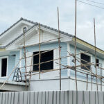 An ADU construction site showing a house being built with scaffolding and wooden poles.