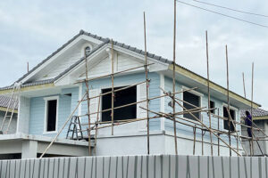 An ADU construction site showing a house being built with scaffolding and wooden poles.