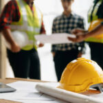 A group of construction workers gathered around a table, discussing plans and collaborating on a project.